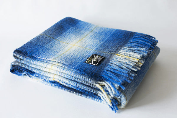 Folded Irish wool blanket with blue checkered pattern and visible label