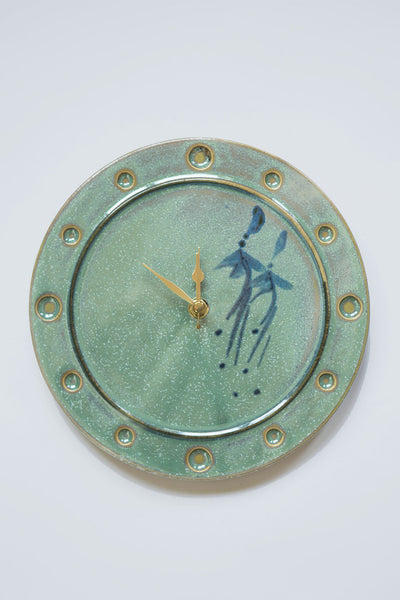 Irish green ceramic clock with two blue fuchsia flowers on the right half and brass hands